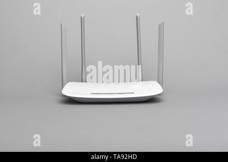 White modern Wi-Fi router with four antennas on gray background. Stock Photo