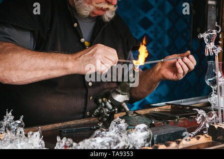 A glassblower makes a glass product. Handwork. Profession or occupation or hobby. Stock Photo