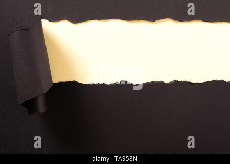 Torn black paper strip yellow background curled Stock Photo