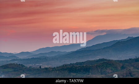 Beautiful nature landscape of mountain range with sunset sky and clouds. Rural village in mountain valley in Thailand. Scenery of mountain layer Stock Photo