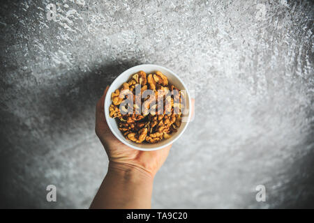 Walnuts in the white bowl on the gray and white background taken from the top. Stock Photo