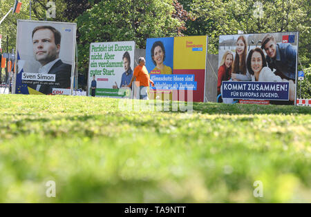 30 April 2019, Hessen, Frankfurt/Main: Michael Belzer and his dog pass election posters of the parties CDU (l-r), Bündnis 90/Die Grünen, FDP and SPD for the European elections in the east of Frankfurt. The direct election to the European Parliament will take place in Germany on 26 May 2019. 4.7 million Hesse are called to vote. Photo: Arne Dedert/dpa Stock Photo