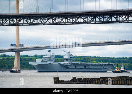 North Queensferry, Scotland, UK. 23rd May, 2019. Aircraft carrier HMS Queen Elizabeth sails from Rosyth in the River Forth after a visit to her home port for a refit. She returns to sea for Westlant 19 deployment and designed to focus on the operations of her F-35 fighter aircraft. Pictured; Carrier passes underneath Queensferry Crossing Bridge at low tide. Credit: Iain Masterton/Alamy Live News Stock Photo