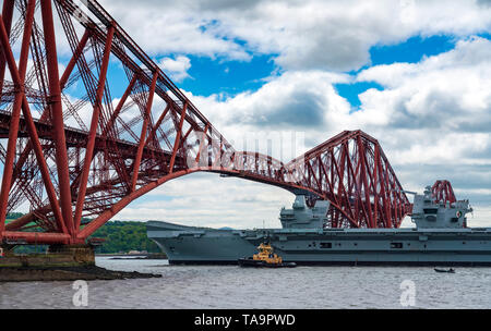 North Queensferry, Scotland, UK. 23rd May, 2019. Aircraft carrier HMS Queen Elizabeth sails from Rosyth in the River Forth after a visit to her home port for a refit. She returns to sea for Westlant 19 deployment and designed to focus on the operations of her F-35 fighter aircraft. Pictured; The Carrier passes below the Forth Bridge at low tide. Credit: Iain Masterton/Alamy Live News Stock Photo