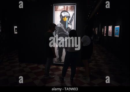 Malaga, Spain. 23rd May, 2019. Visitors seen looking at a painting during the exhibition.'Bansky The art of Protest' at cultural center 'La Térmica' is an exhibition showing for the first time in Malaga. the work of famous and mysterious British street artist 'Bansky', display more than 40 creations such originals works, sculptures, videos and photographs provide by international private collections including the original print of ''NiÃ±a con globo' Credit: Jesus Merida Luque/SOPA Images/ZUMA Wire/Alamy Live News Stock Photo