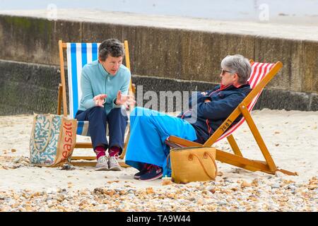 Lyme Regis, Dorset, UK. 23rd May, 2019. UK Weather. Two women sitting in deck chairs on the beach at the seaside resort of Lyme Regis in Dorset enjoying an afternoon of warm hazy sunshine. Picture Credit: Graham Hunt/Alamy Live News Stock Photo