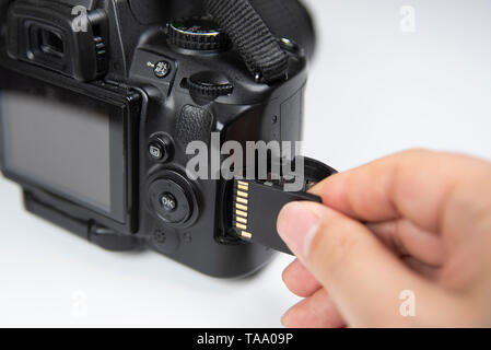 Photographer hand holding SD memory card insert DSLR camera Stock Photo
