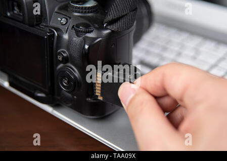 Photographer hand holding SD memory card insert DSLR camera Stock Photo