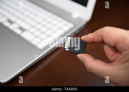 Human hand plugging in an SD media card into the personal laptop computer Stock Photo