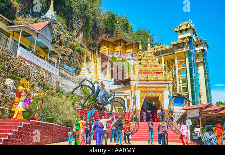 PINDAYA, MYANMAR - FEBRUARY 19, 2018: The gate of Pindaya caves, decorated with pyatthat roof, the statues of spider and prince with bow and arrows ar Stock Photo