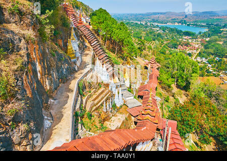 Enjoy the scenery of Pindaya, its lush greenery, bright blue lake and roofs of Buddhist Cave temple from the steep mountain slope, Myanmar. Stock Photo