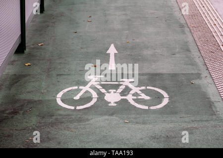 Bike lane symbol with a direction arrow on ground. Bicycle trail road sign on modern bridge for bike and cyclists in urban city. Travel, tourism.
