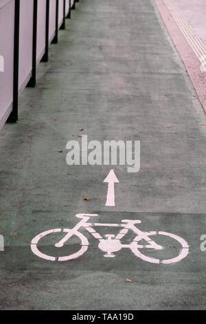 Bike lane symbol with a direction arrow on ground. Bicycle trail road sign on modern bridge for bike and cyclists in urban city. Travel, tourism.