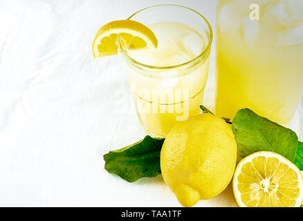 fresh organic lemonade in a jar with lemons and leaves and a glass of lemonade on a white background with copy space Stock Photo