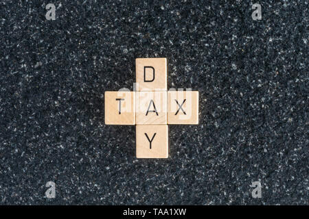 Wood letters forming tax day cross on a black table background. The deadline to pay taxes. Stock Photo