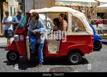 Ostuni, Italy - 24 June 2018: tourists in the characteristic streets of the historic center of Ostuni. Some use special three-wheeled motorcycles to r Stock Photo