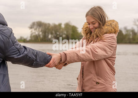 A young woman tries to pull her partner into the water Stock Photo