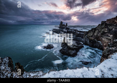 Londrangar volcanic rock formations in the sea in snow at winter time in Snaefellsnes Peninsula, Iceland Stock Photo