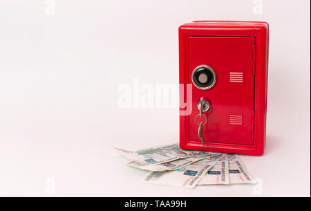 red safe on a fan of russian money on white background. bank with key Stock Photo