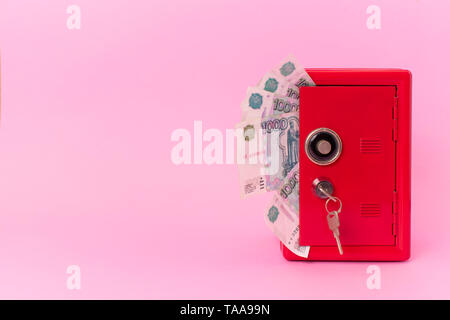 red safe on a fan of russian money on white background. bank with key Stock Photo