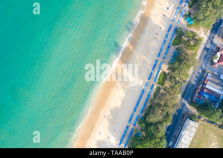 Aerial view of people swimming on the pink swim ring in the transparent turquoise sea in Phuket, Thailand.
