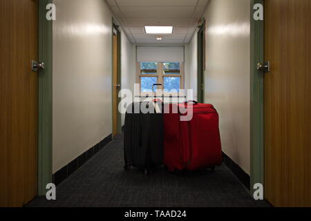 Two suitcases waiting outside in the dorm hallway on move out day Stock Photo