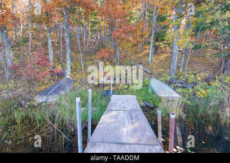 Old dock and boat on small remote lake in Northern Wisconsin with fall trees and fall color on shoreline Stock Photo