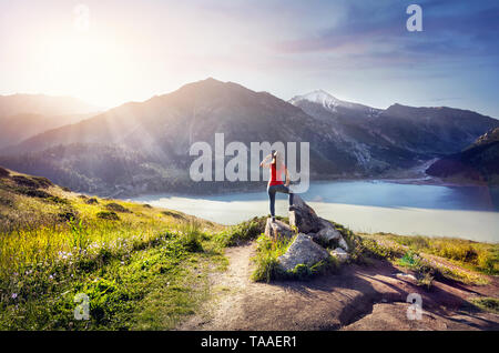Tourist woman with hat enjoying sunrise on the lake in the mountain Stock Photo