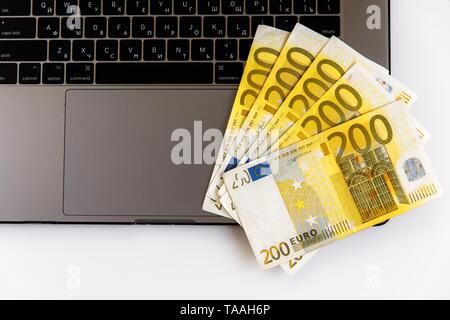 Banknotes of different denominations lie near the laptop Stock Photo