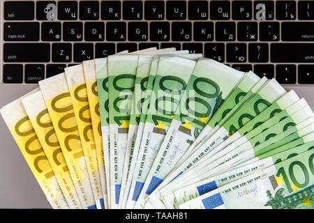 Banknotes of different denominations lie near the laptop Stock Photo