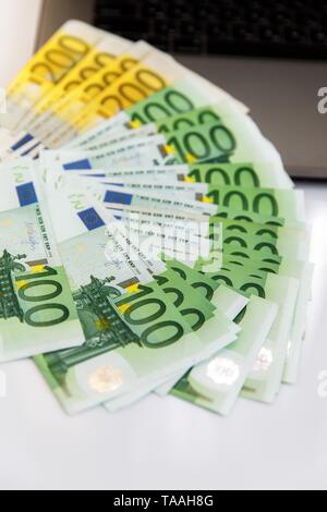 Banknotes of different denominations lie near the laptop Stock Photo
