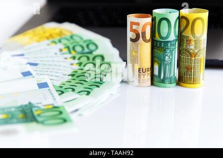 Banknotes of different denominations lie near the laptop Stock Photo