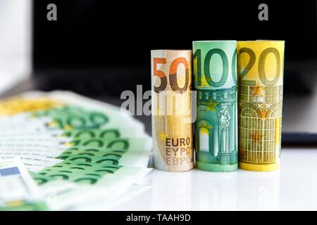 Banknotes of different denominations lie near the laptop Stock Photo