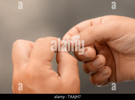 Fisherman tying sharp hook on fishing line in outdoors, close-up. Stock Photo