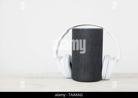 Smart speaker device and hearphones against a white background. Empty copy space for Editor's text Stock Photo