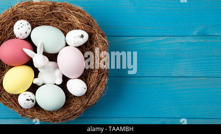 Happy easter nest blue wooden background with colorful easter eggs and easter bunny Stock Photo