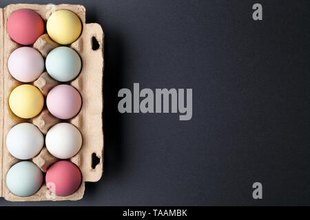 Colorful easter eggs in an egg carton on graphite texture background Stock Photo
