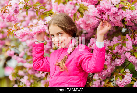 Little girl enjoy spring. Kid on pink flowers of sakura tree background. Kid enjoying pink cherry blossom. Tender bloom. Pink is the most girlish color. Bright and vibrant. Pink is my favorite. Stock Photo