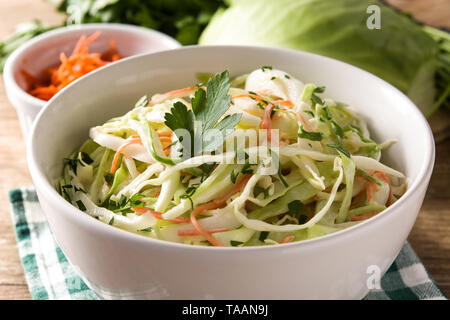 Coleslaw salad in white bowl on wooden table. Close up Stock Photo