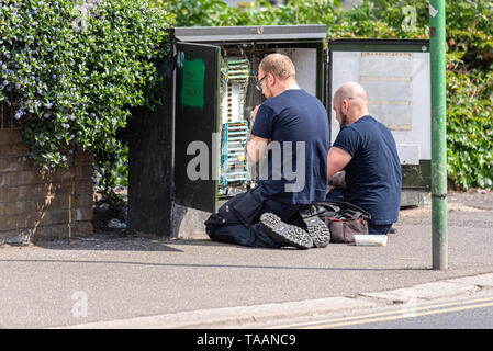Two telecoms engineers working in a junction box. Telecom, telecommunications junction box open with engineer technicians working Stock Photo
