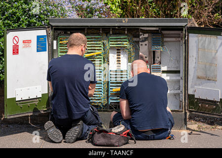 Two telecoms engineers working in a junction box. Telecom, telecommunications junction box open with engineer technicians working Stock Photo