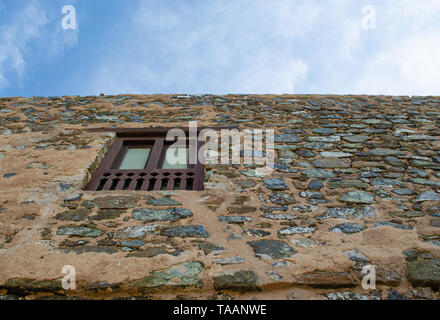 Wooden window on a stone wall of the historic Muttrah Fort in Muscat, Oman. Low angle view. Stock Photo