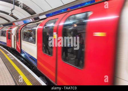 London tube platform edge. Painted warning on the floor. Train passing by . Stock Photo