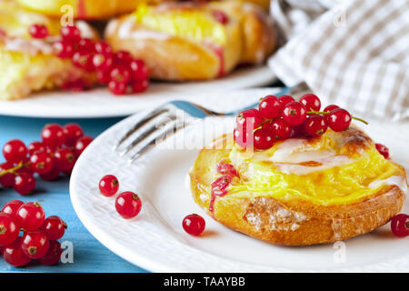 Puff pastry with pudding and red currants on a blue wooden table. Fruit cake. Stock Photo