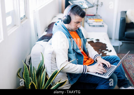 handsome young man using laptop computer with headset Stock Photo