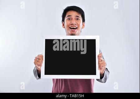 Happy young handsome asian man holding and showing blank blackboard or board ready for your text. Copy space Stock Photo