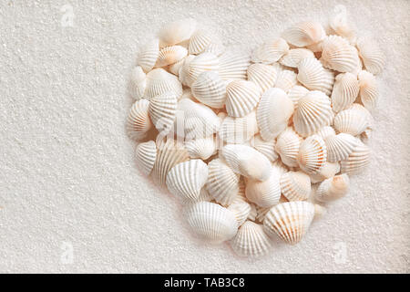 On white sand shells lie in heart form Stock Photo