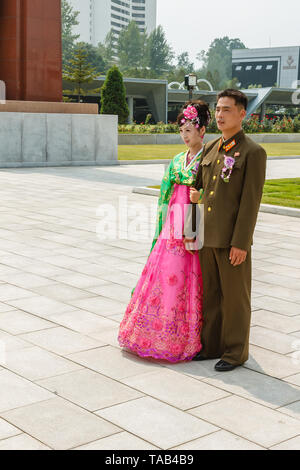 Pyongyang, North Korea - July 29, 2014: Young Korean couple in Victorious Fatherland Liberation War Museum. Newlyweds are photographed against the bac Stock Photo