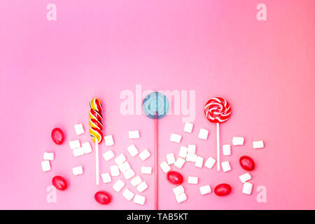 Flat lay composition with yummy lollipops and marshmallows and space for text on pink background Stock Photo