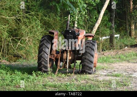 An old rusty tractor sits abandoned with a flat tire in a farm field. Stock Photo